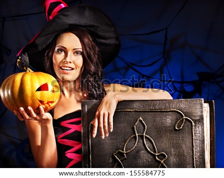 Happy witch woman holding old book and pumpkin