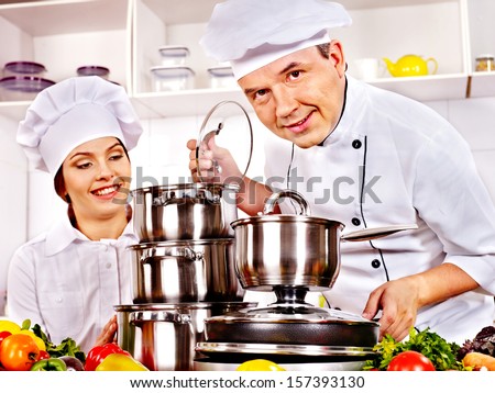 Happy man in chef hat and woman cooking at kitchen.