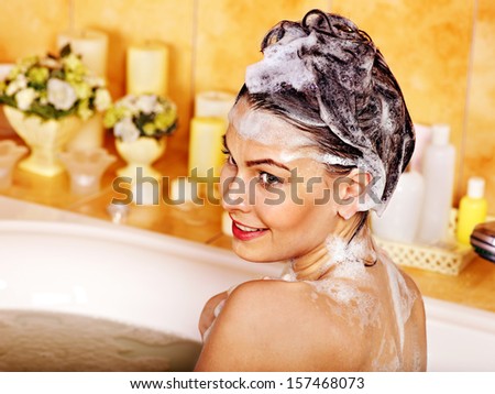 Woman washing hair in bubble bath.