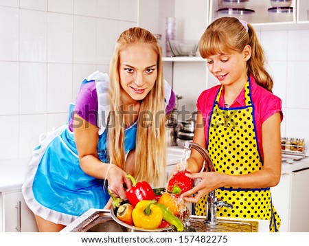 Mother and daughter washing fruit at kitchen.