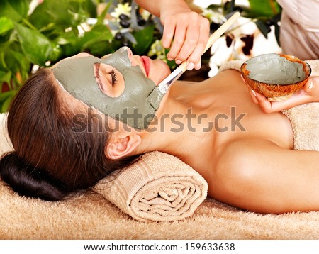 Beautiful Woman Having Clay Facial Mask Apply By Beautician.