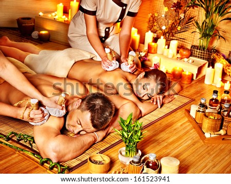 Man and woman getting herbal ball massage in bamboo spa.