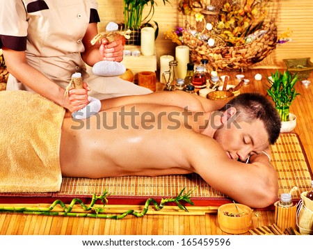 Man getting herbal ball massage treatments  in spa..