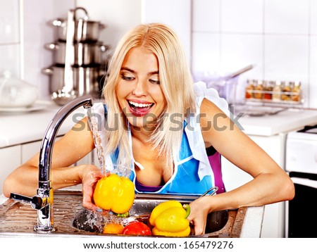 Happy woman washing fruit at kitchen.
