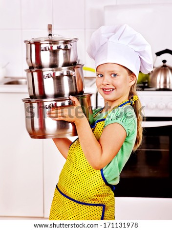 Child wearing hat and apron cooking at kitchen.