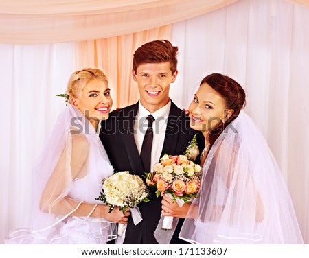 Happy wedding man and two bride holding flower bouquet.