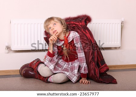 Girl in coat warm  near radiator.  Energy crisis.