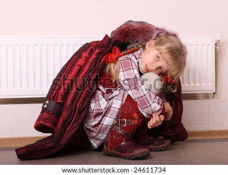 Girl in coat warm  near radiator.  Energy crisis.
