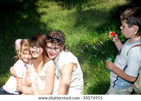 Happy family and children with soap bubbles in park.