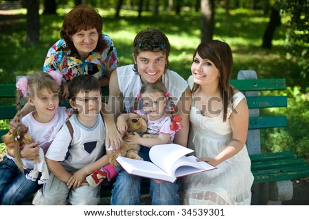 Happy family with  child and grandmother in outdoor read book. Upbringing.