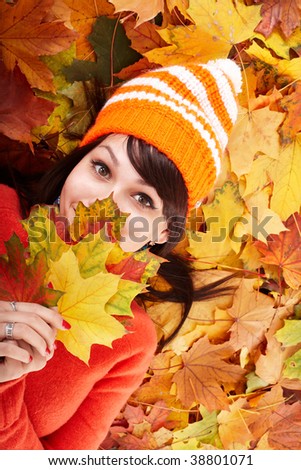 Girl in autumn orange hat on leaf group. Outdoor.