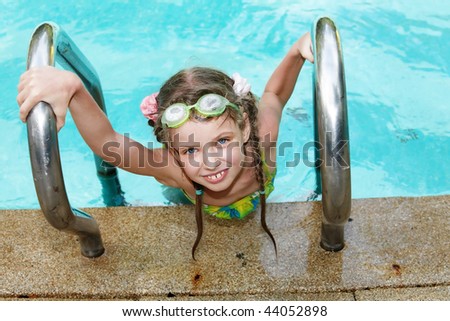 Girl in sport protective goggles leaves pool.