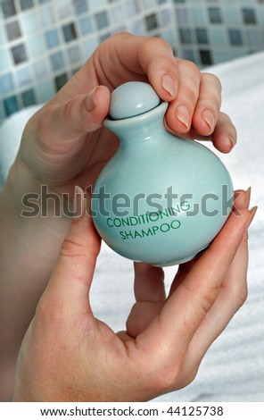 Green shampoo bottle in hand. Spa beauty.