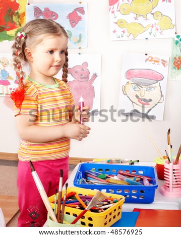 Child preschooler with colour pencil in play room.