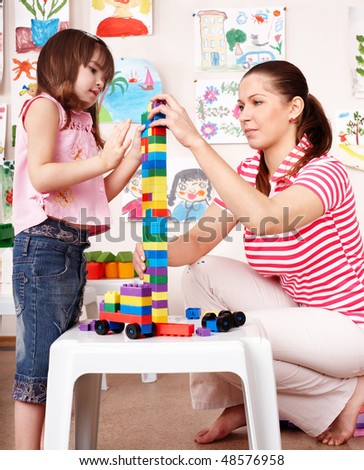 Child with wood block and construction set in play room. Preschool.