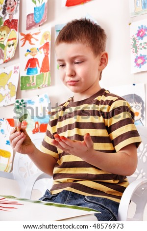 Child with picture and brush in play room. Preschool.