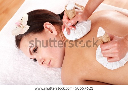 Girl  having Thai herb compress massage in beauty spa. Body care.