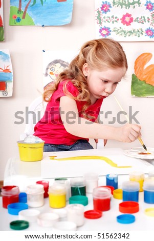 Child with brush draw picture  in play room. Preschool.