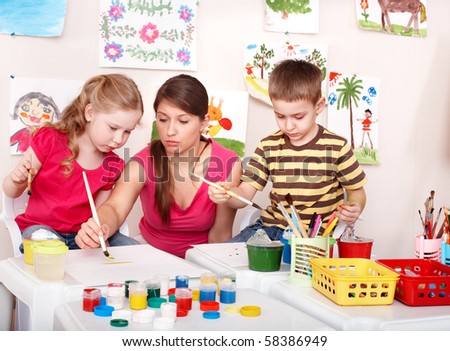 Children with teacher painting in play room. Preschool.
