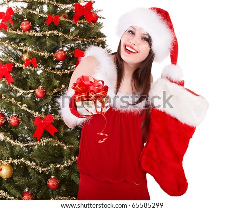 Girl in santa hat holding christmas socks and gift box by christmas tree.  Isolated.