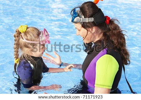 Child with mother in swimming pool learning snorkeling.