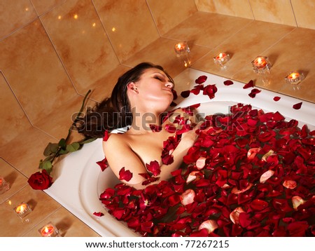 Woman relaxing in bath with rose petal.
