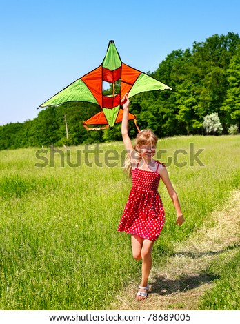 Child flying kite outdoor. little girl running across  green grass.