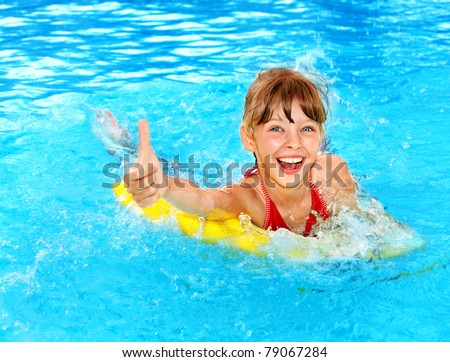 Child sitting on inflatable ring in swimming pool.