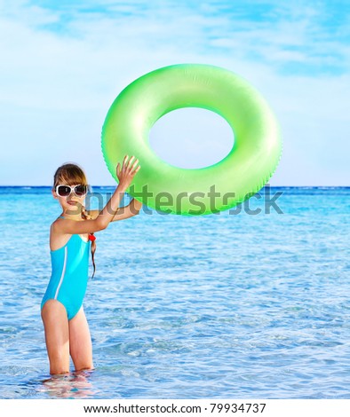Children holding inflatable ring in sea.
