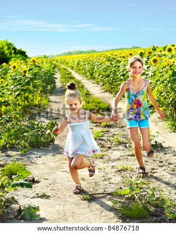 Group children running across sunflower field outdoor.