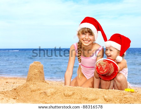 Children in santa hat playing on  beach. Summer New Year.