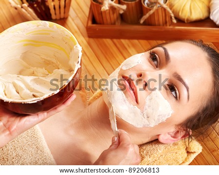 stock photo Beautiful girl having clay facial mask apply by beautician