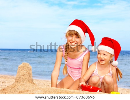Children in santa hat playing on  beach. Summer New Year.
