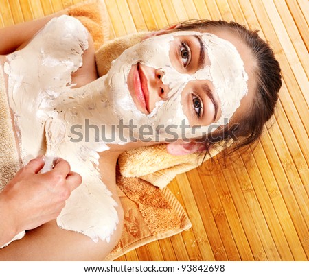 stock photo Beautiful girl having clay facial mask and body apply by