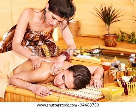 Young woman getting massage in bamboo spa.