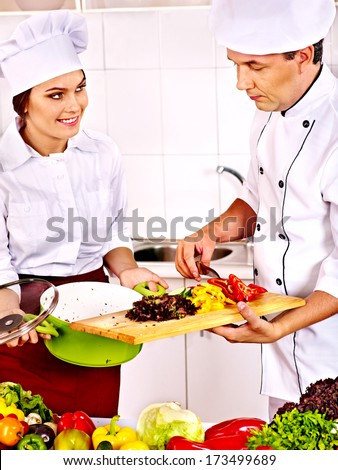 Happy man and woman in chef hat cooking food.
