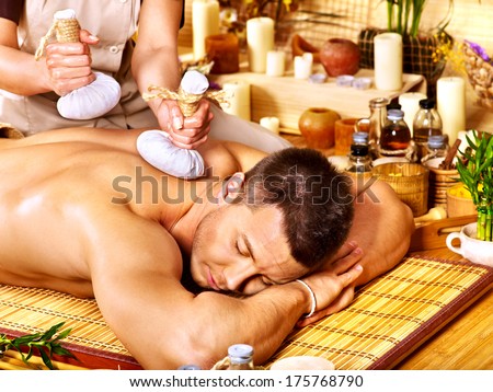 Man getting herbal ball massage treatments  in spa.