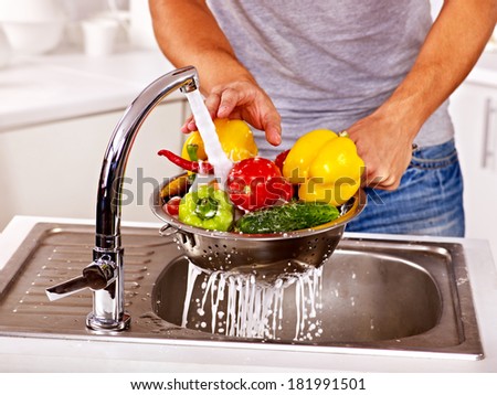 Happy man washing fruit at kitchen.
