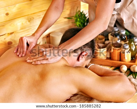 Man getting massage in bamboo spa. Female therapist.