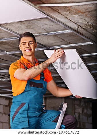Man in builder uniform installing suspended ceiling