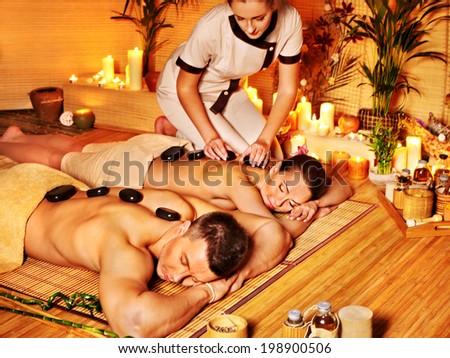 Woman and man getting stone therapy massage in bamboo spa.