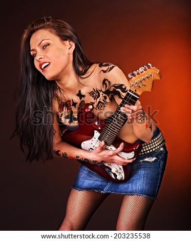 Aggressive young woman with tattoo playing guitar.