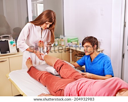 Doctor bandaging foot patient in hospital.