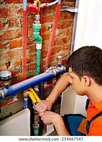 Men builder fixing heating system with special tool.