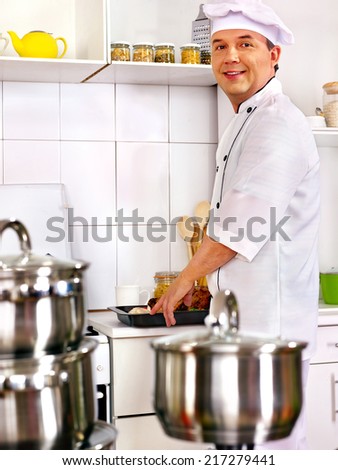 Happy man in chef hat cooking .