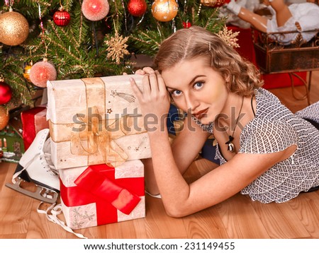 Woman receiving gifts under Christmas tree.