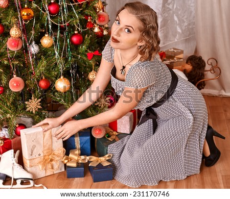 Woman receiving gifts under Christmas tree.