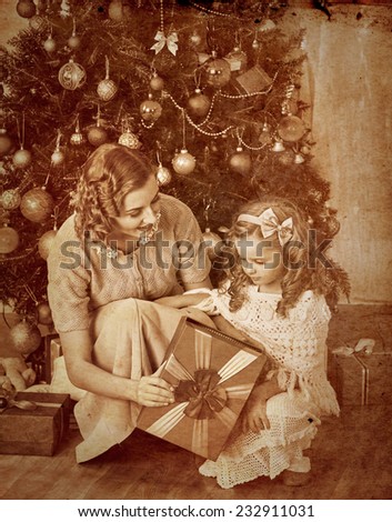 Happy child with mother receiving gifts under Christmas tree.