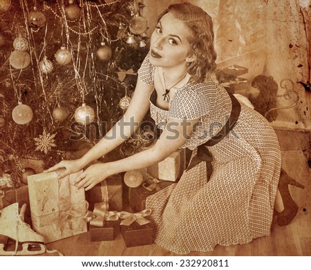 Woman receiving gifts under Christmas tree. Sepia toned.