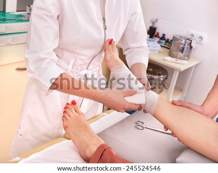 Doctor bandaging foot patient in hospital.